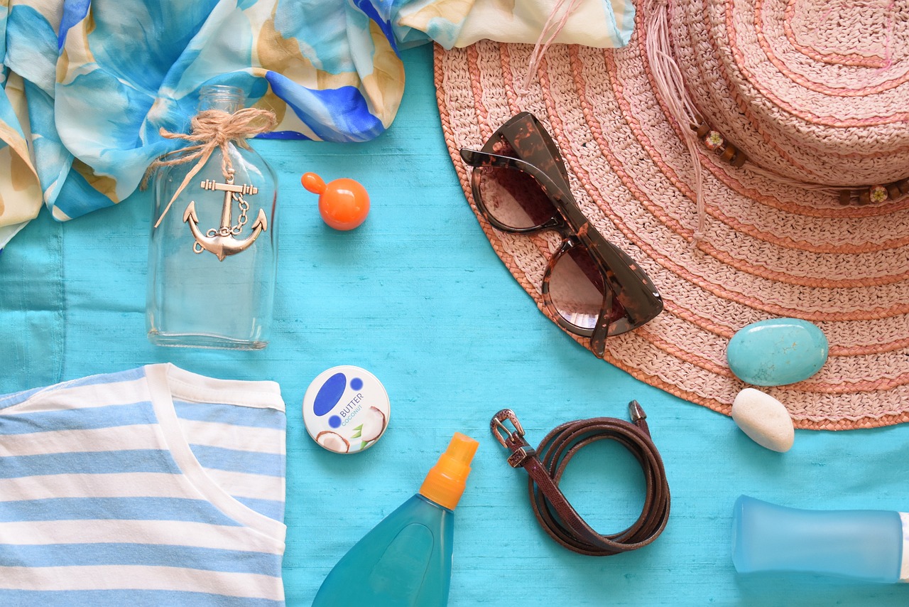 Beach attire, sunscreen, and more on top of a towel.