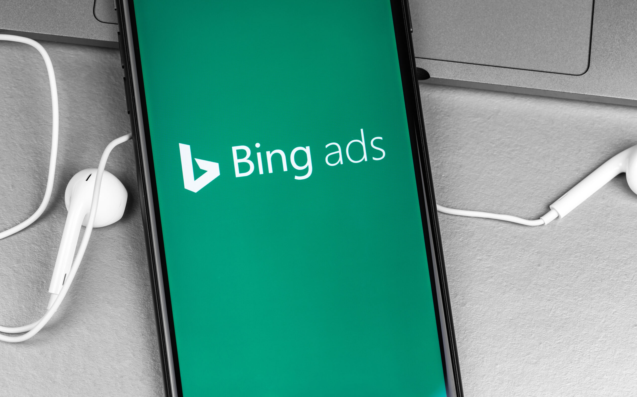 Bing Ads app logo on screen smartphone iPhone with headphones Ea