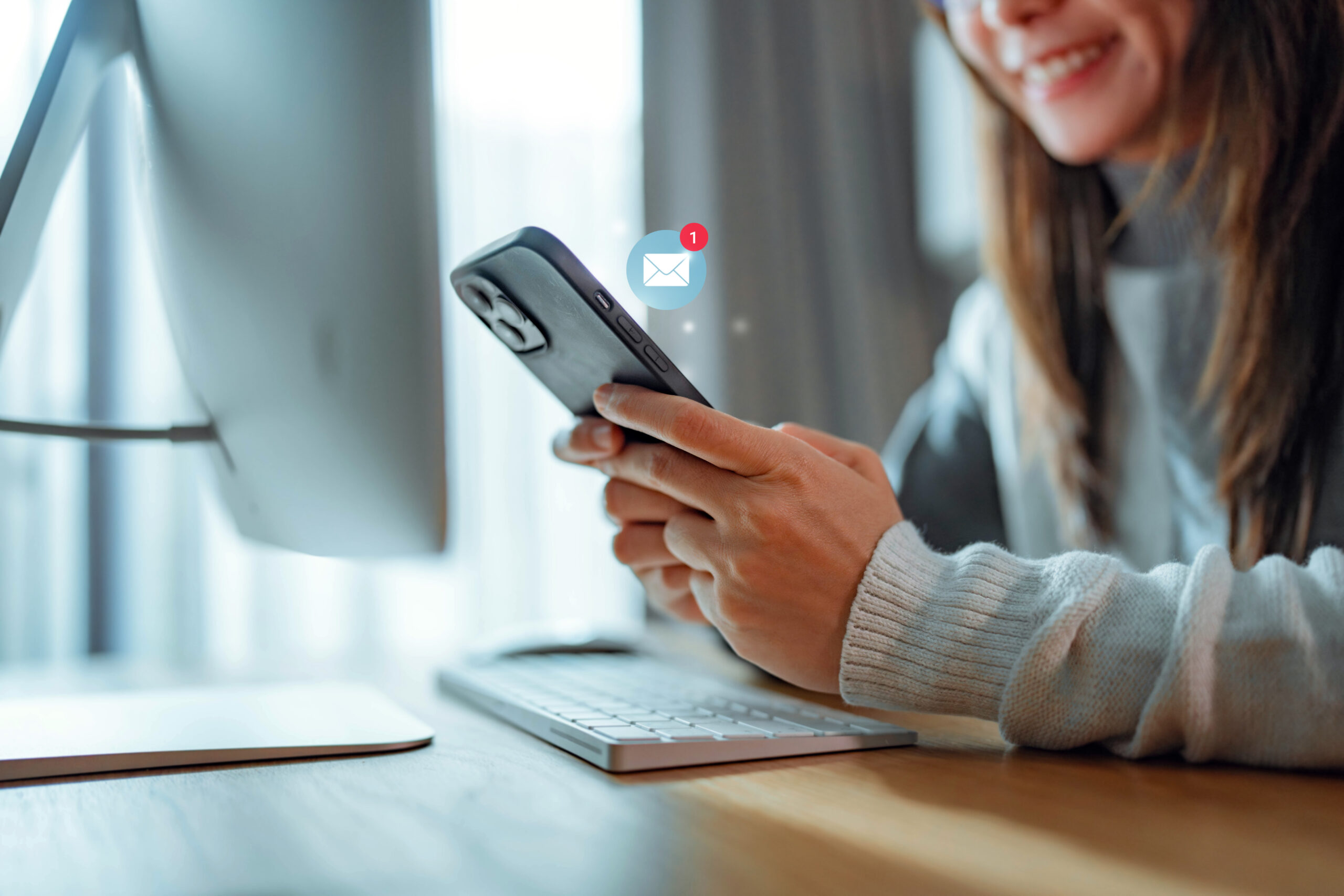 A woman smiles while looking at her smartphone.