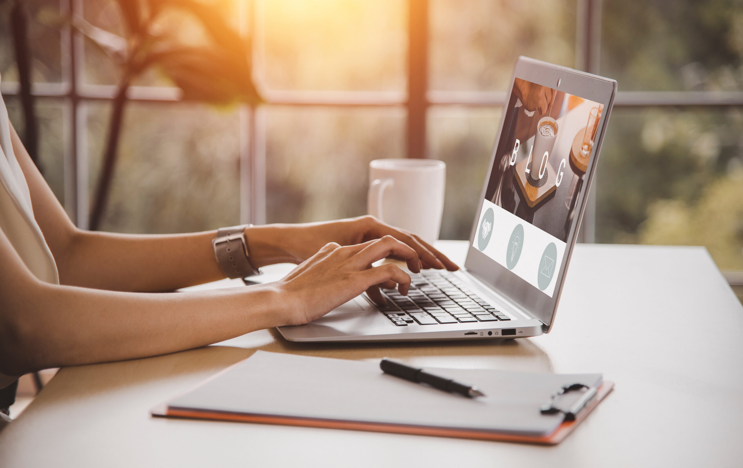 A person sits at a desk while looking at a blog on their laptop.