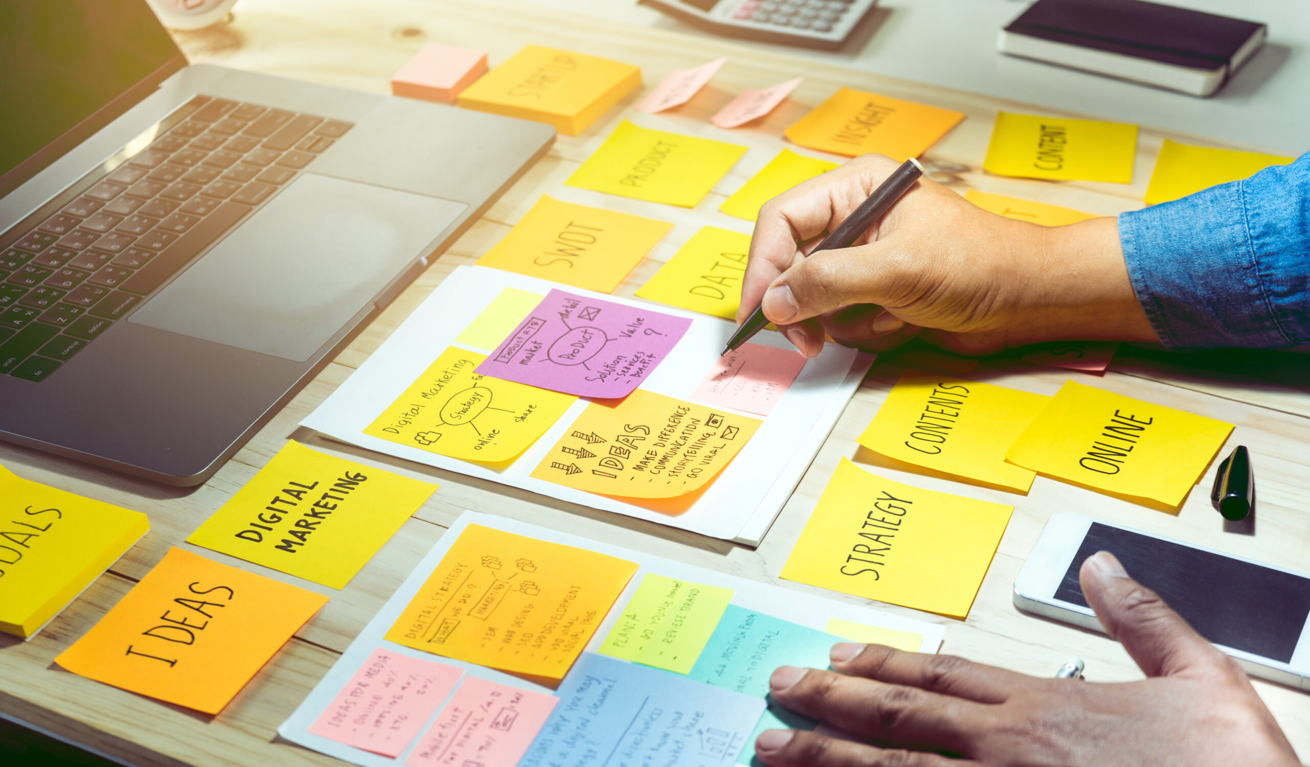 A person writing down ideas on a sticky note.