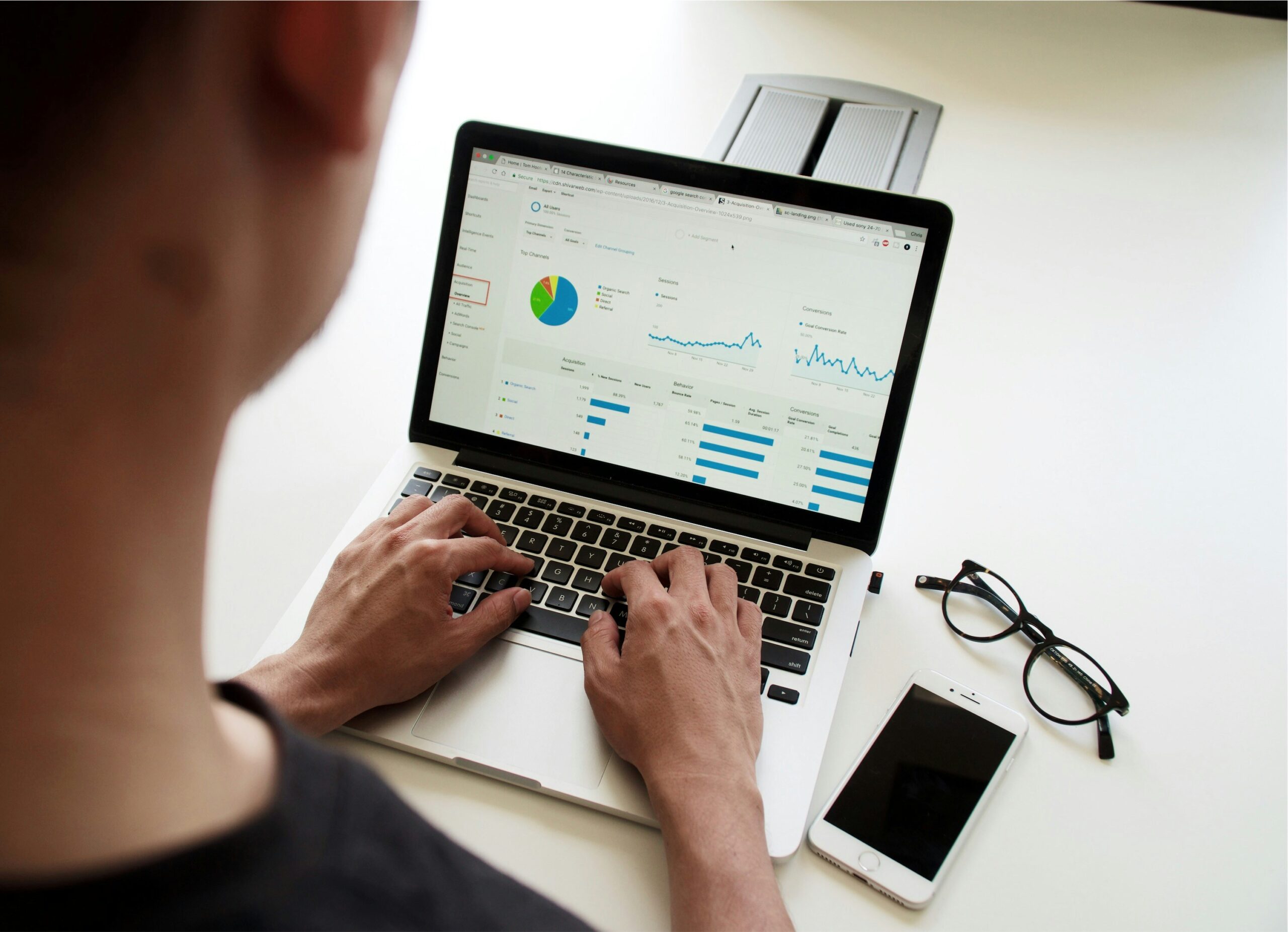 A person uses a laptop that shows a variety of statistics, charts, and metrics on the screen.