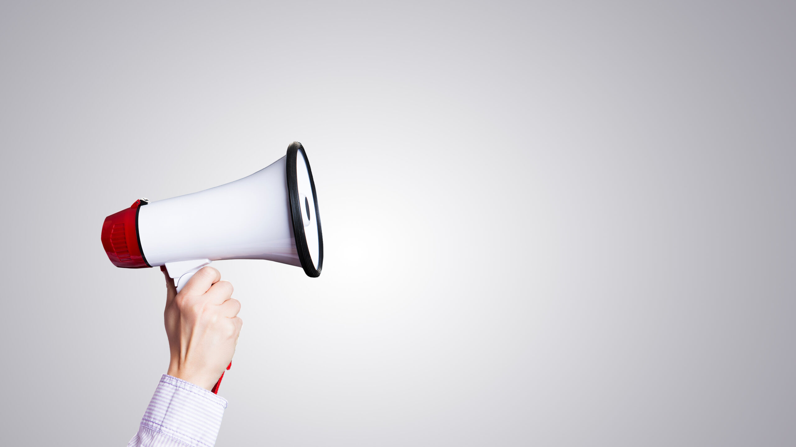 A megaphone is held up in front of a blank white background.