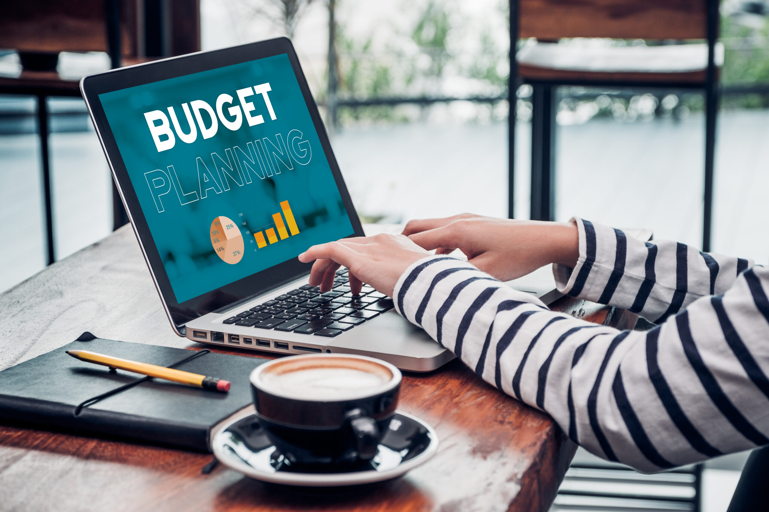 A person works on a laptop with the screen showing a budget planning graphic.