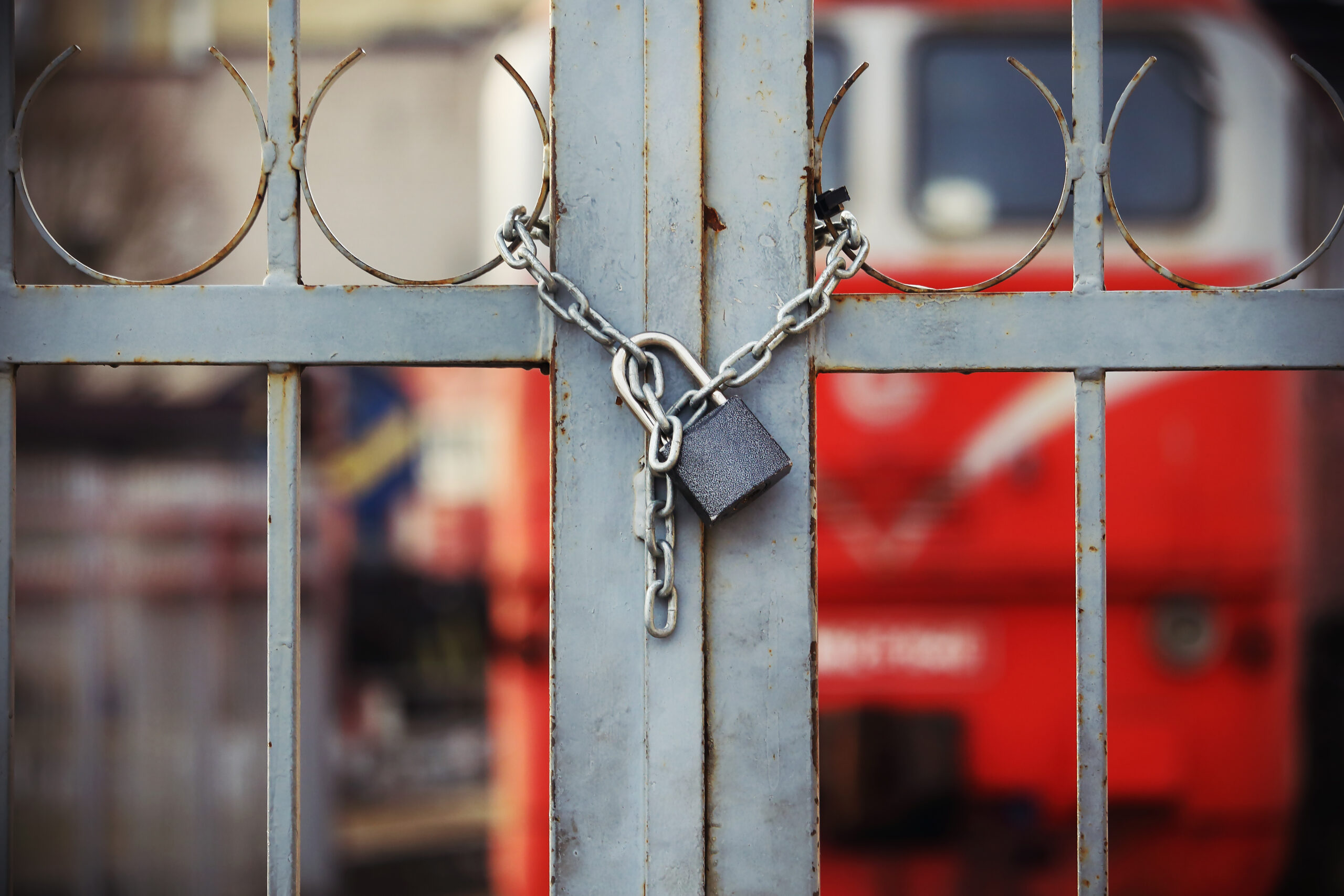 A metal gate is closed shut with a chain and padlock.