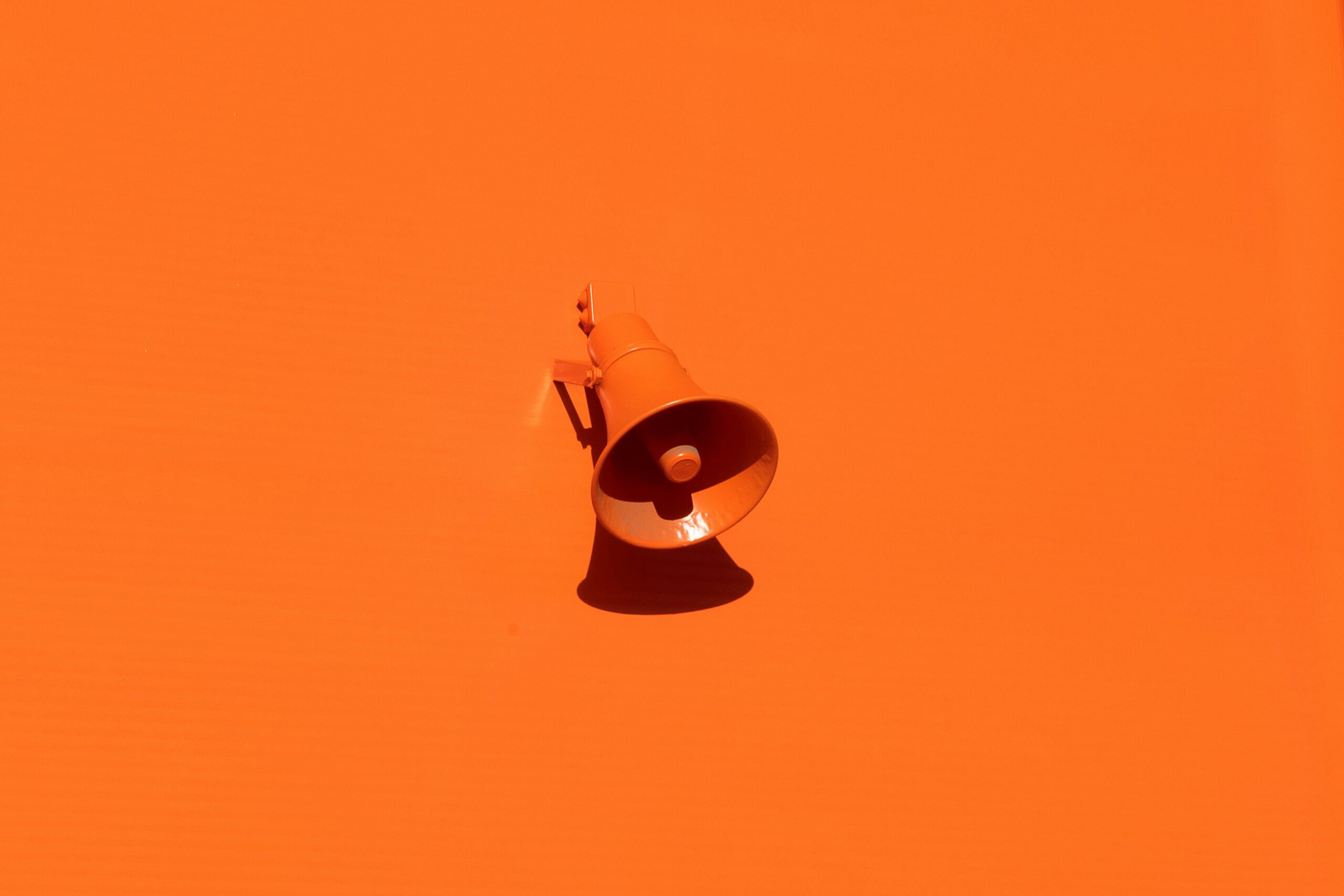An orange megaphone pictured in front of an orange background.