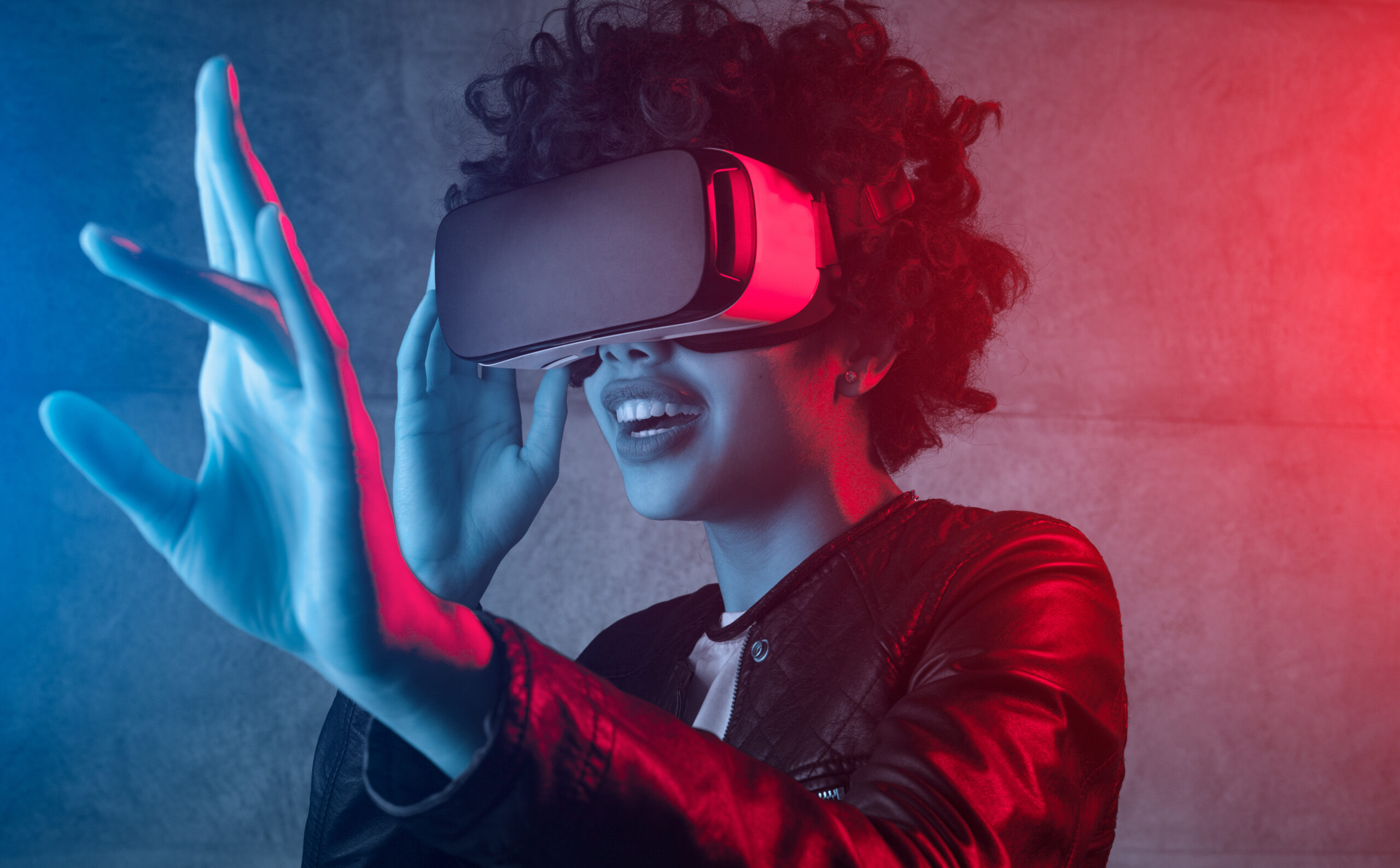 A woman wearing a VR headset stands in front of a concrete background.