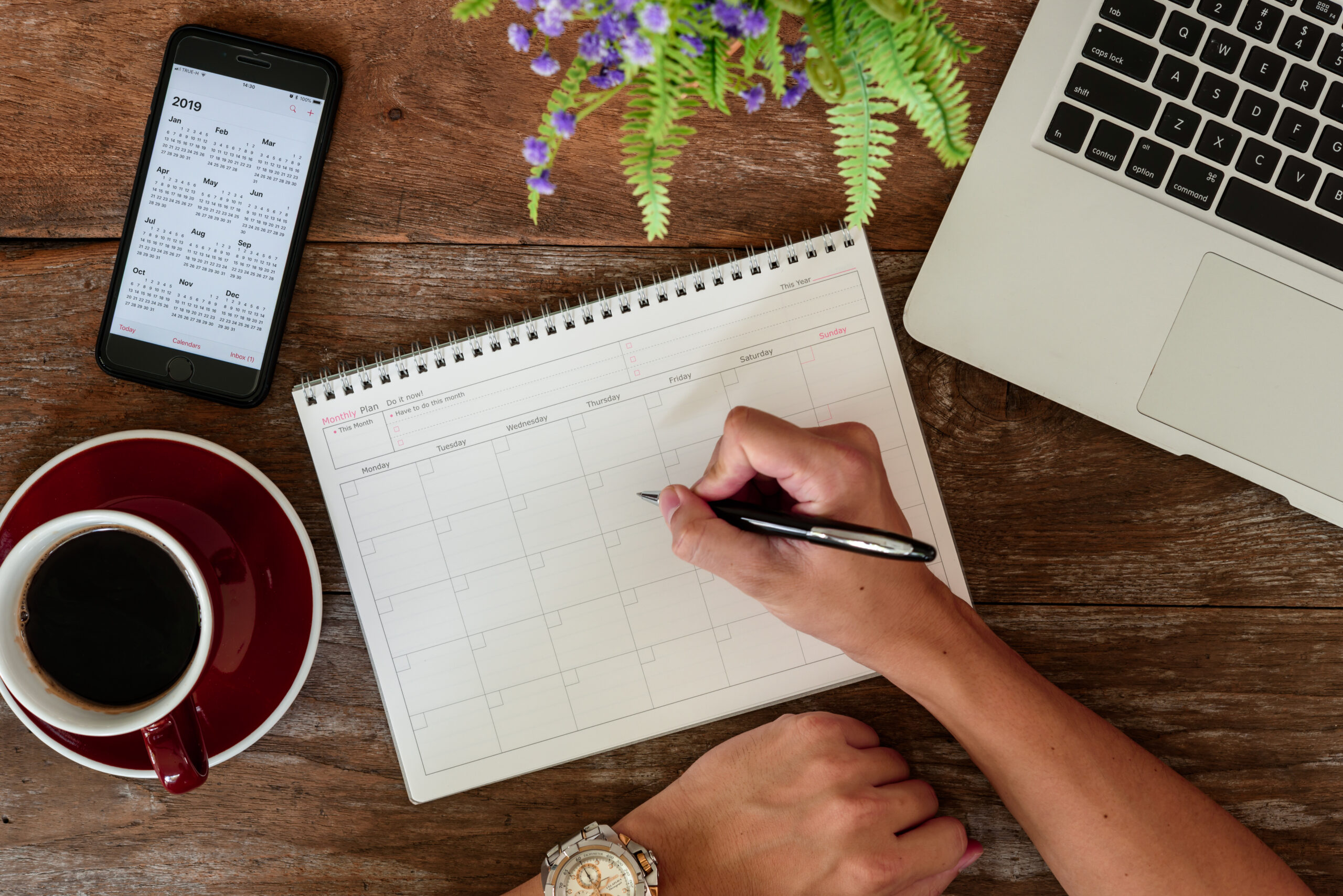 A person starts to write on a calendar with a pen.