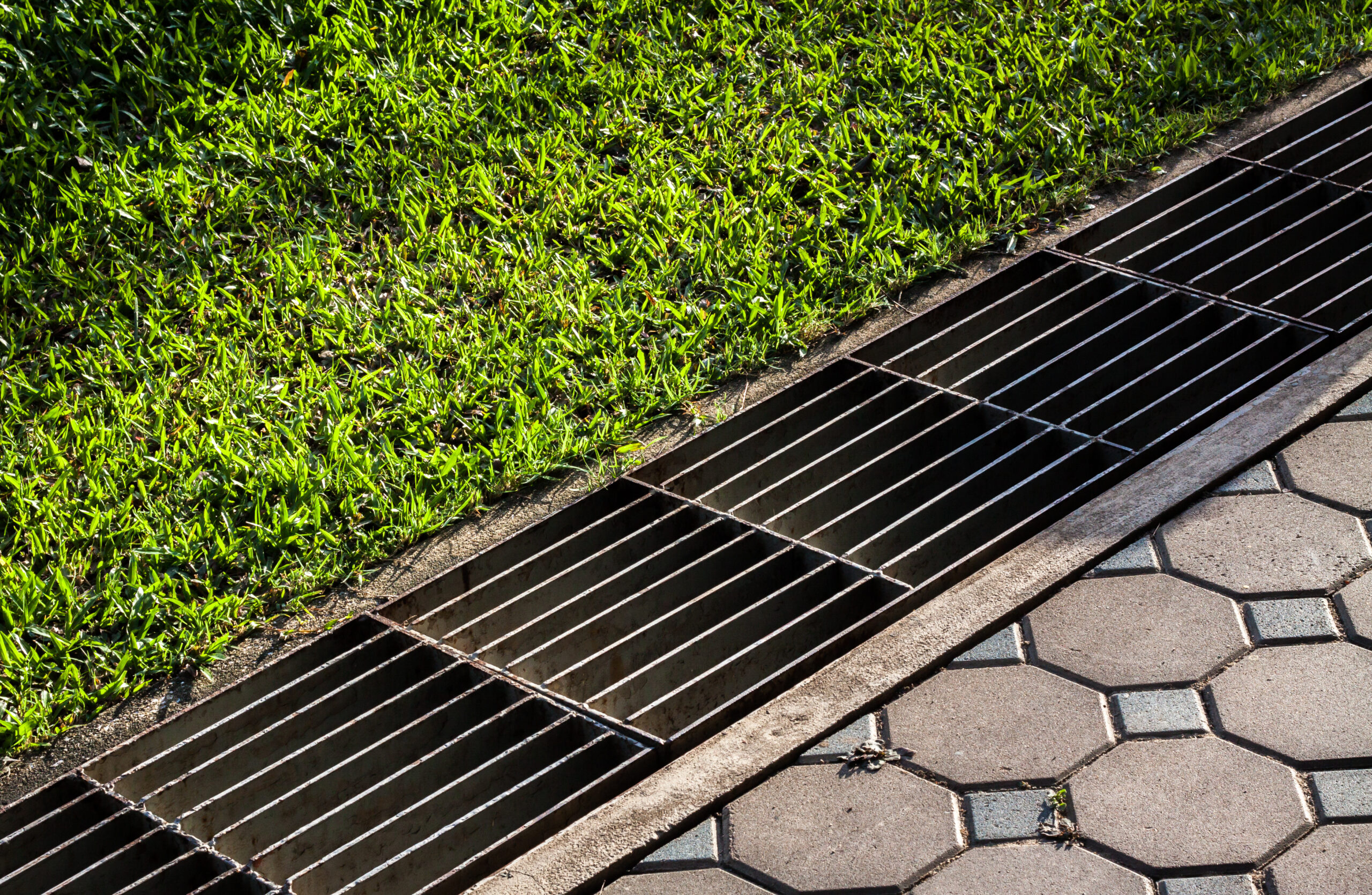 waterway and road - grass. Aqueduct between nature and city. water drain in garden field. Steel rusty grating in the Grass garden and concrete. Manhole cover metal and way - grass. drainage. sewer.